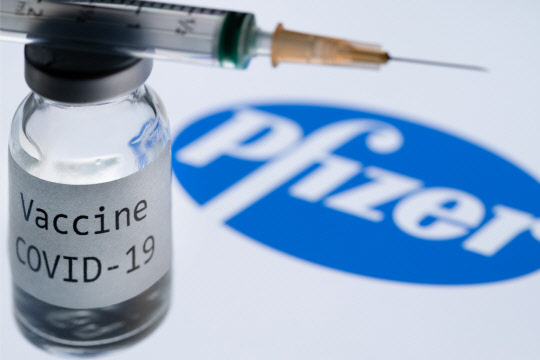 (FILES) In this file photo illustration taken on November 23, 2020, shows a syringe and a bottle reading "Covid-19 Vaccine" next to the Pfizer company logo. - The vaccine advisory committee of the US Food and Drug Administration (FDA) will meet December 10, 2020 after poring over data from clinical trials carried out by Pfizer/BioNTech.  The FDA should then give its authorization for emergency use of the vaccine. That decision could come "within days after the advisory committee" meets, Health Secretary Alex Azar said.  On December 17, the same process will unfold for the Moderna vaccine. (Photo by JOEL SAGET / AFP)